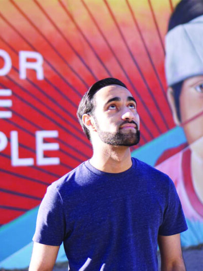 a young man stands looking upwards in front of a brightly colored mural