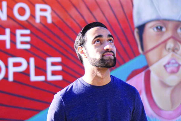 a young man stands looking upwards in front of a brightly colored mural