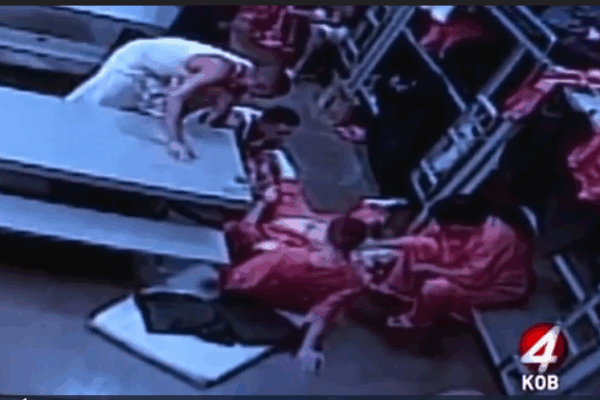 Fellow inmates tend to Douglas Edmisten as he lays on the ground in pain.