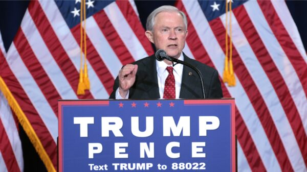 AG Jeff Sessions behind a podium speaking at a Trump Pence political rally