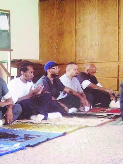 Tremaine praying alongside fellow inmates