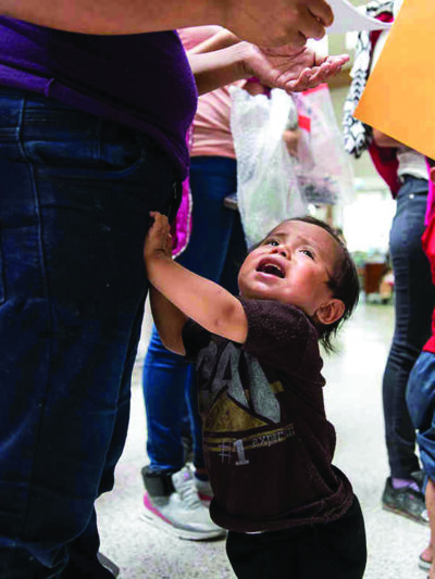 Young child grabbing his parent's leg, crying