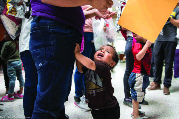 Young child grabbing his parent's leg, crying