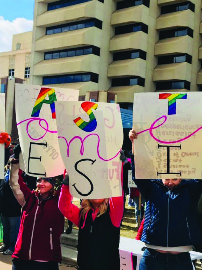 Women holding a sign that says "Women Resist"