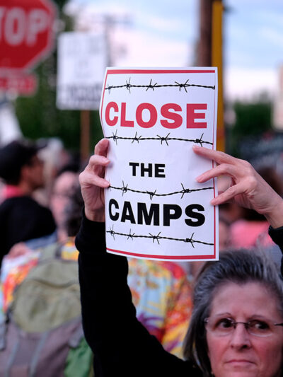 Woman holds sign that reads "Close the Camps" outside of the Immigration and Customs Enforcement (ICE) office in Portland