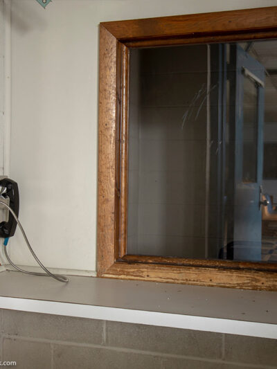 Phone next to window used by visitors to prison to communicate with inmates behind glass.