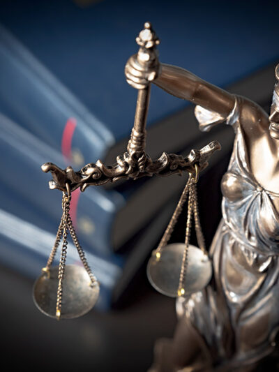 A statue of Lady Justice with a stack of books in the background.