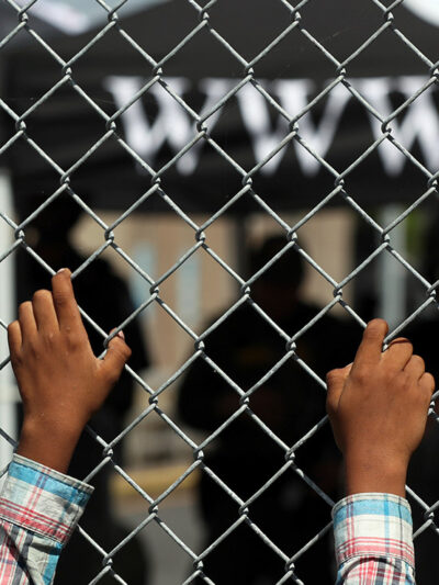 A migrant leans on a fence of the Gateway International Bridge that connects downtown Matamoros, Mexico with Brownsville, Texas.