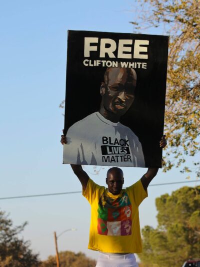 Photo of Clifton White holding a "free Clifton White" poster