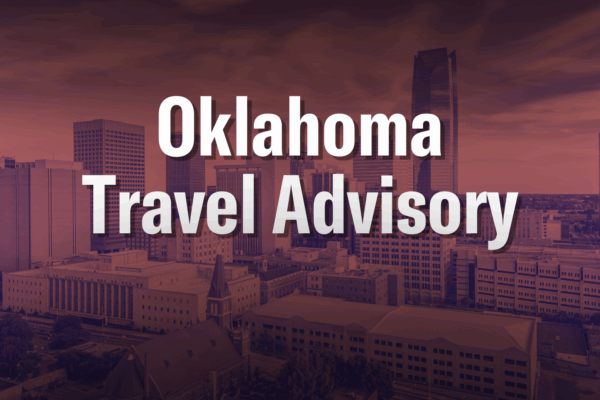 Red and blue duotone graphic of Oklahoma City skyline with white text reading "Oklahoma Travel Advisory" in all caps.