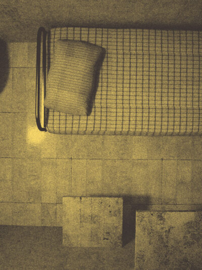 An overhead view of a solitary jail cell with a single metal bed frame and a thin mattress. The cell includes a basic toilet and sink, all enclosed within the bare, confined space, evoking a stark and austere atmosphere.