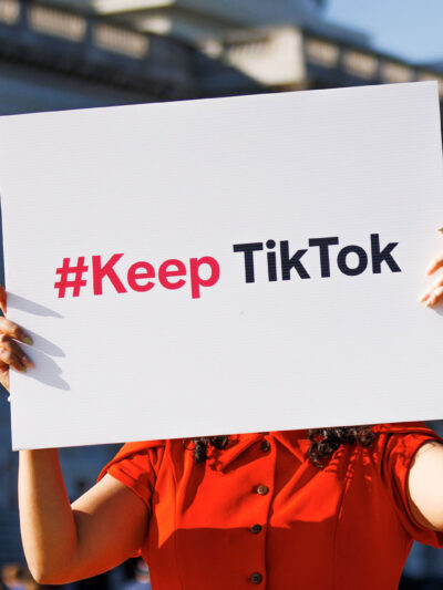 A person is holding a sign outside the Capitol Building that reads " #Keep TikTok".