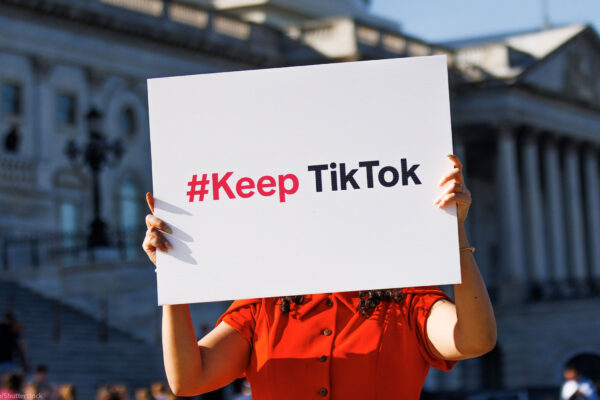 A person is holding a sign outside the Capitol Building that reads " #Keep TikTok".