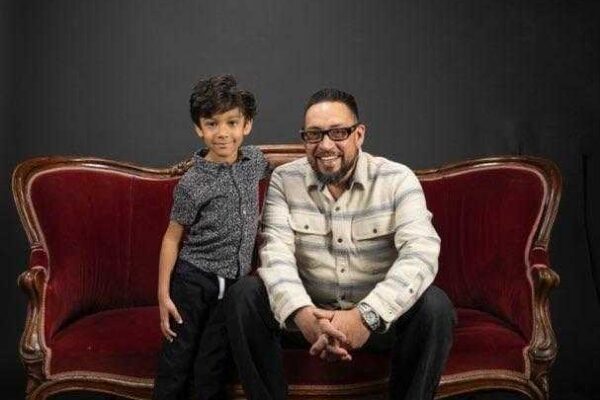 Adam Griego cuddles with his grandson on a velvet couch