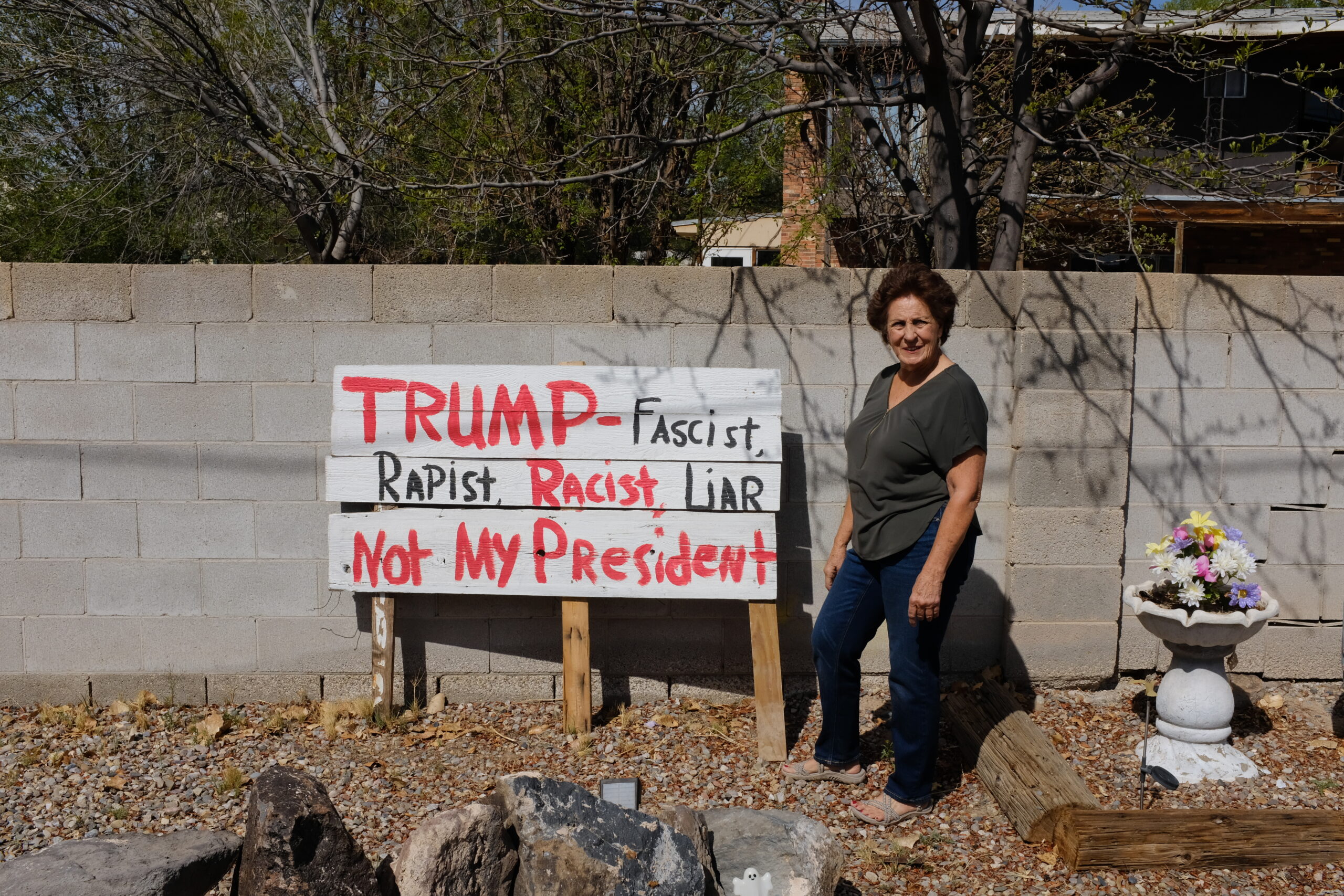 A photo of Rita Padilla-Gutiérrez standing in front of her sign that reads: "Trump, racist, rapist, not my president"