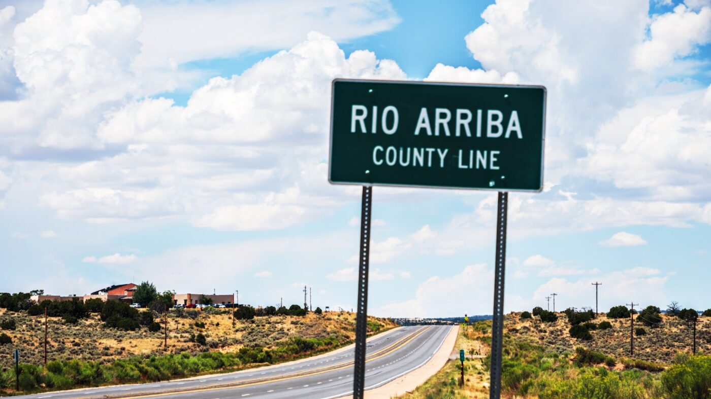 A road sign showing the Rio Arriba county line with Lybrook elementary just beyond it.