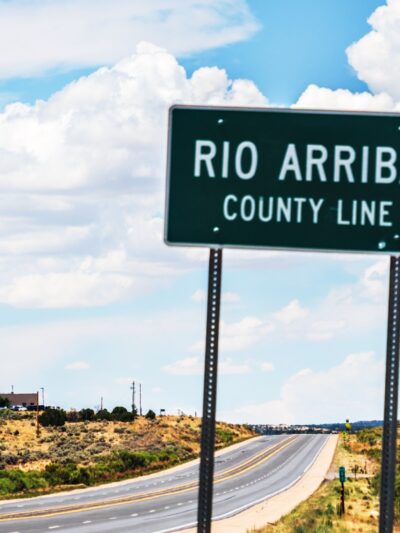 A road sign showing the Rio Arriba county line with Lybrook elementary just beyond it.