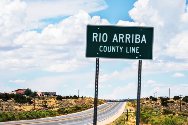 A road sign showing the Rio Arriba county line with Lybrook elementary just beyond it.