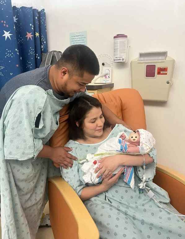 An image of Paulo next to his wife, Alejandra, as they hold their newborn infant.