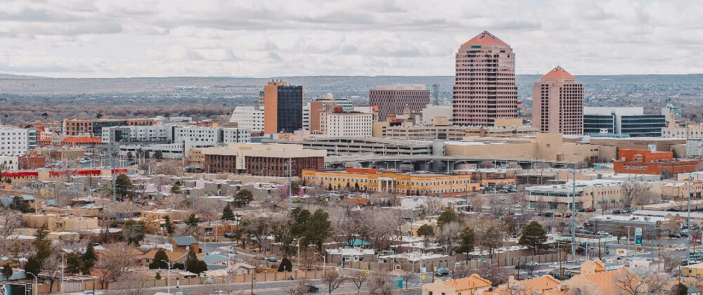 A wide shot of the Albuquerque skyline with scattered clouds in the sky.