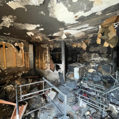 photo taken of the charred remains of the Coleman's home. Various items of burned material are shown among the soot.