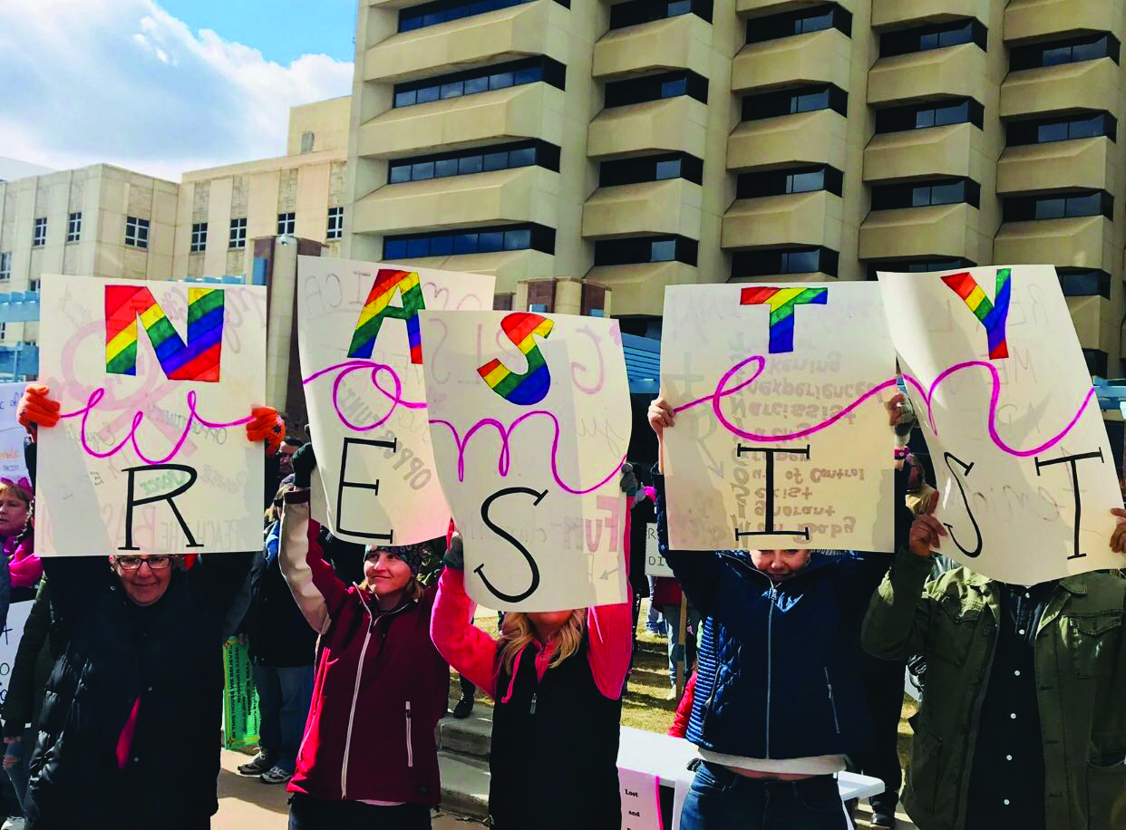 Women holding a sign that says "Women Resist" Women holding a sign that says "Women Resist"