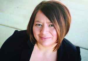 Photo: a woman in a black top with a short bob looks at the camera