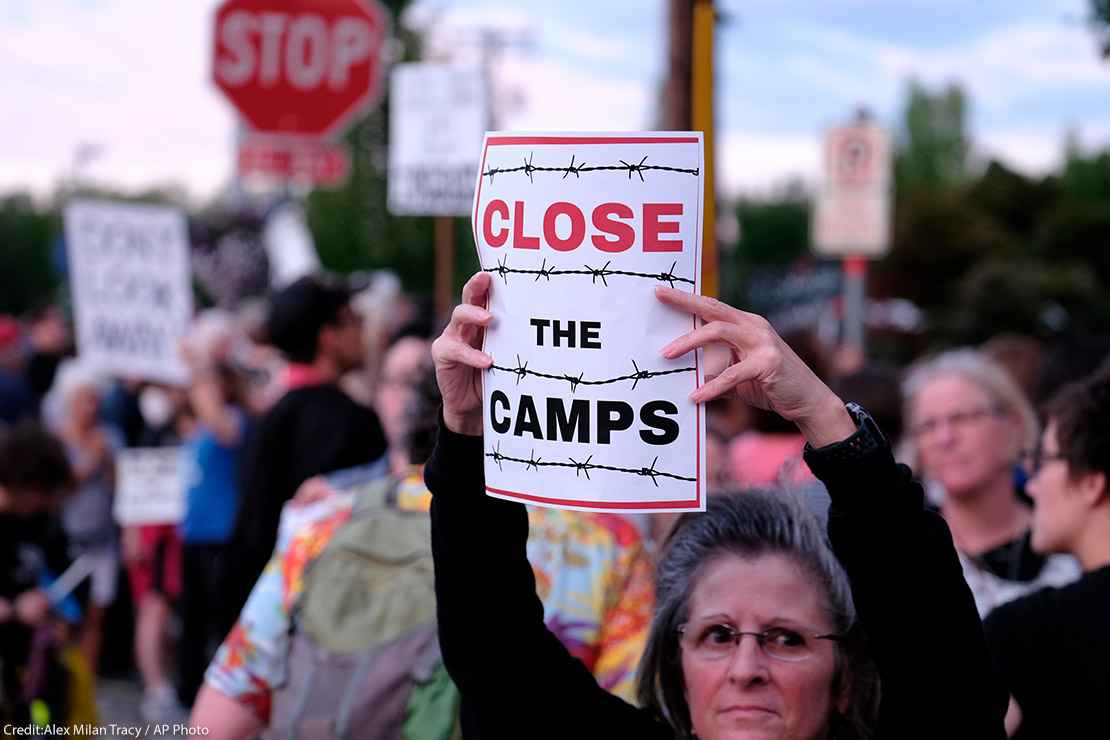 Woman holds sign that reads "Close the Camps" outside of the Immigration and Customs Enforcement (ICE) office in Portland