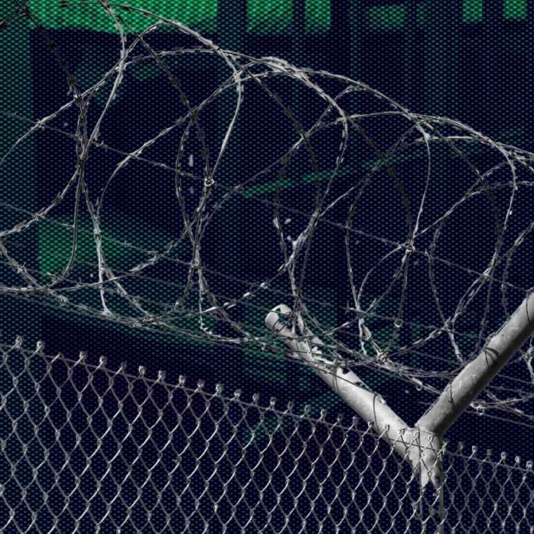 A photo of a prison fence in front of a dark and ominous view of a prison.