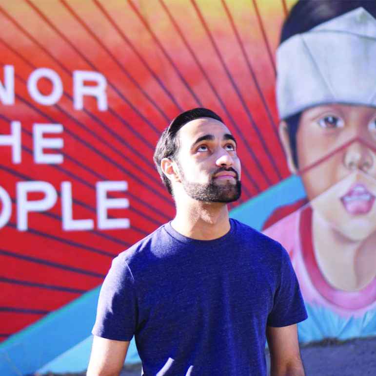 a young man stands looking upwards in front of a brightly colored mural