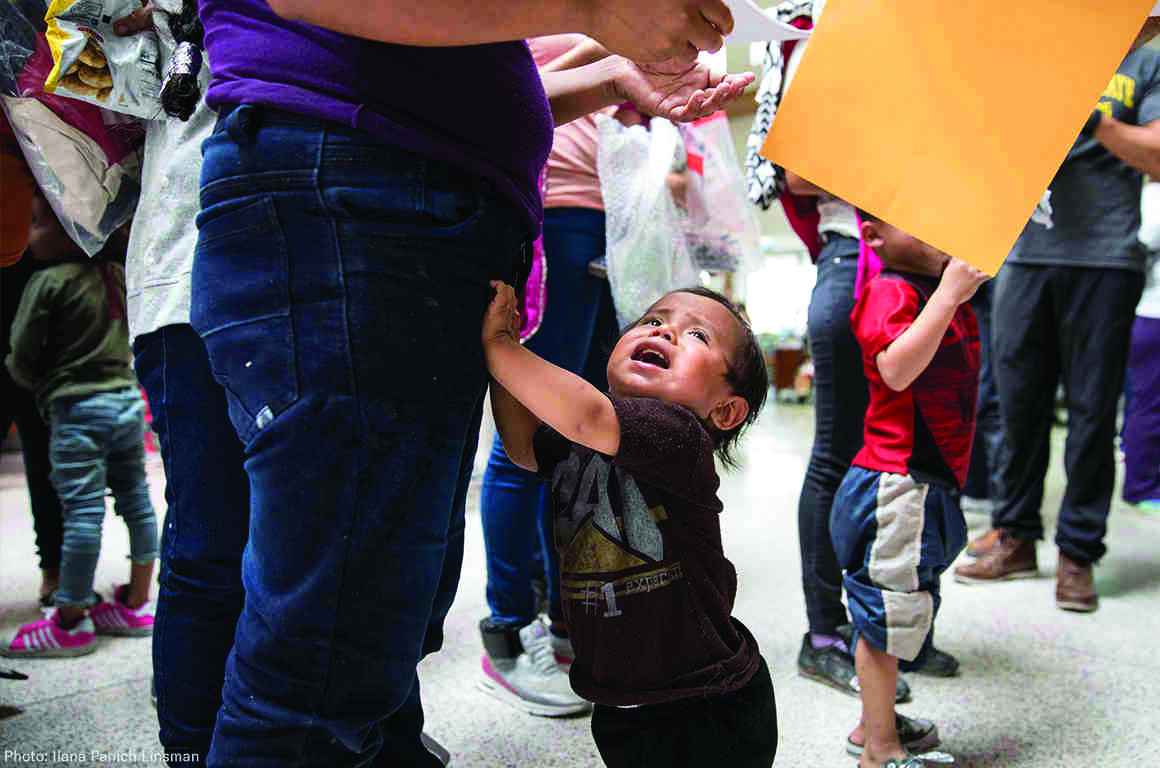 Young child grabbing his parent's leg, crying 