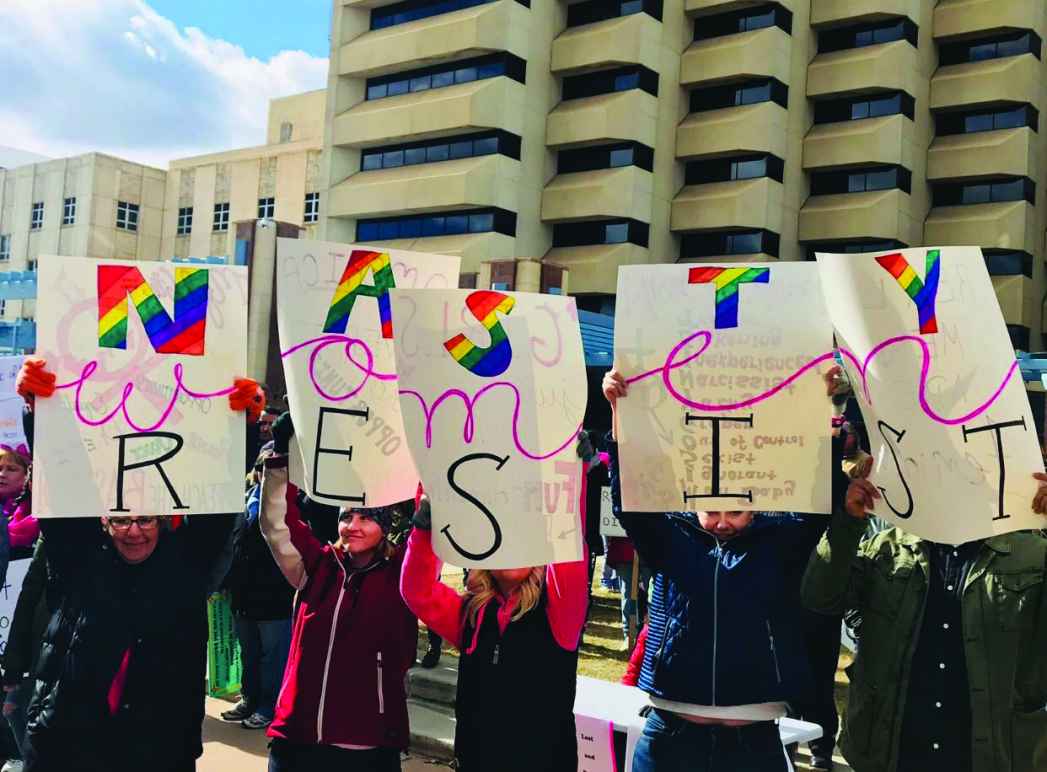 Women holding a sign that says "Women Resist" 