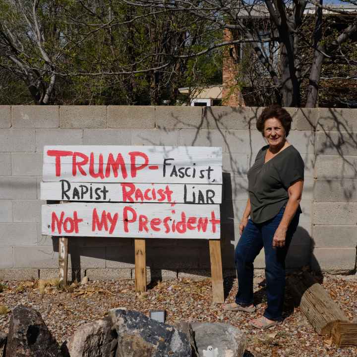 A photo of Rita Padilla-Gutiérrez standing in front of her sign that reads: "Trump, racist, rapist, not my president"