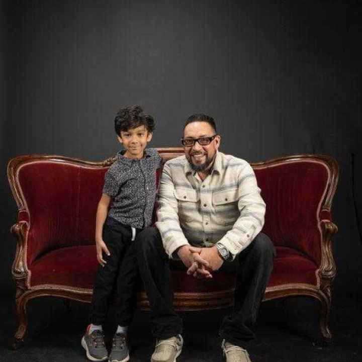 Adam Griego cuddles with his grandson on a velvet couch