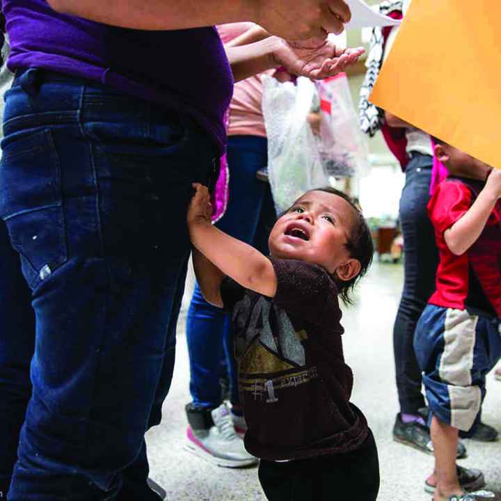 Young child grabbing his parent's leg, crying 