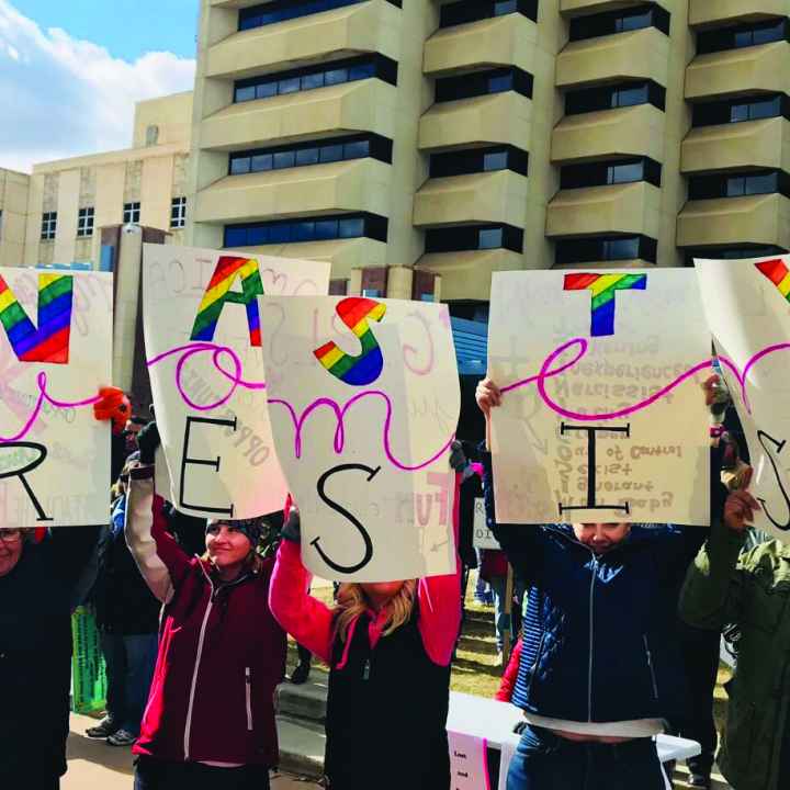 Women holding a sign that says "Women Resist" 